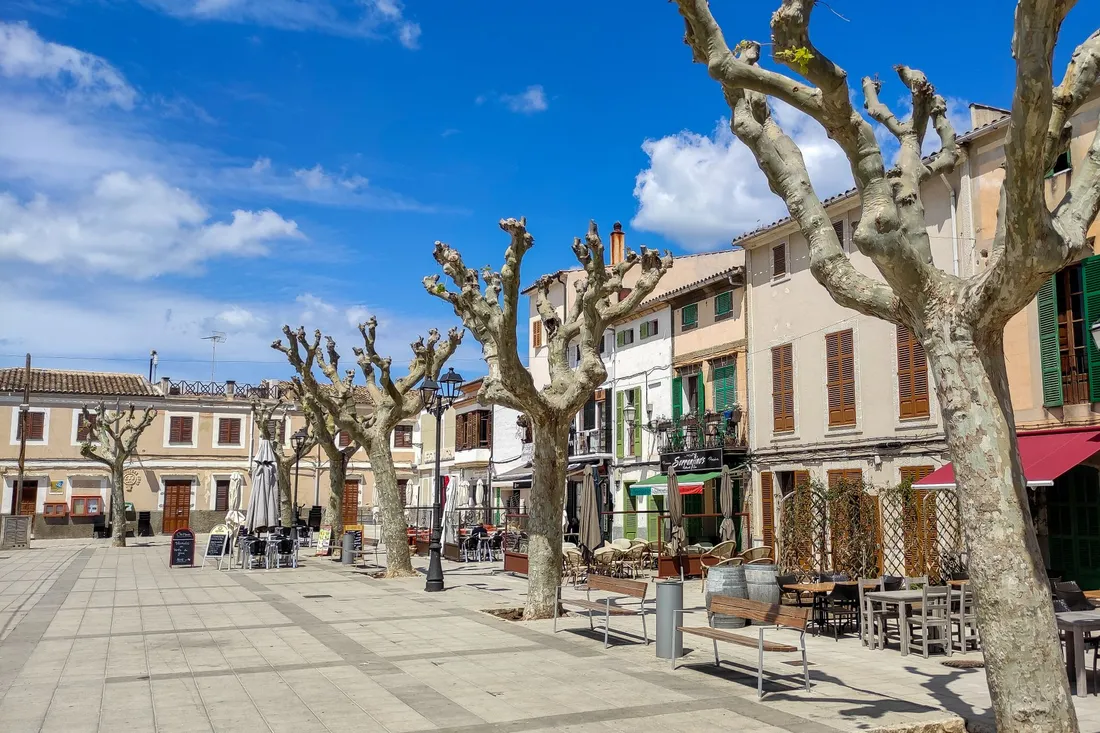 Belebter Stadtplatz mit Cafés und Menschen in einem Neuköllner Kiez